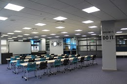 4 rows of desks with 8 chairs, each, facing a projector board
